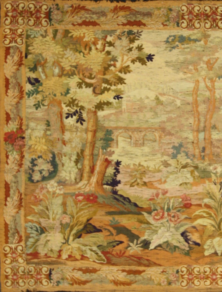 This antique European tapestry has a scenic landscape image of trees, flowers, and a bridge.

Explore your interior design options by browsing a huge selection of  tapestries with Esmaili Rugs & Antiques. If you want to bring old world charm into