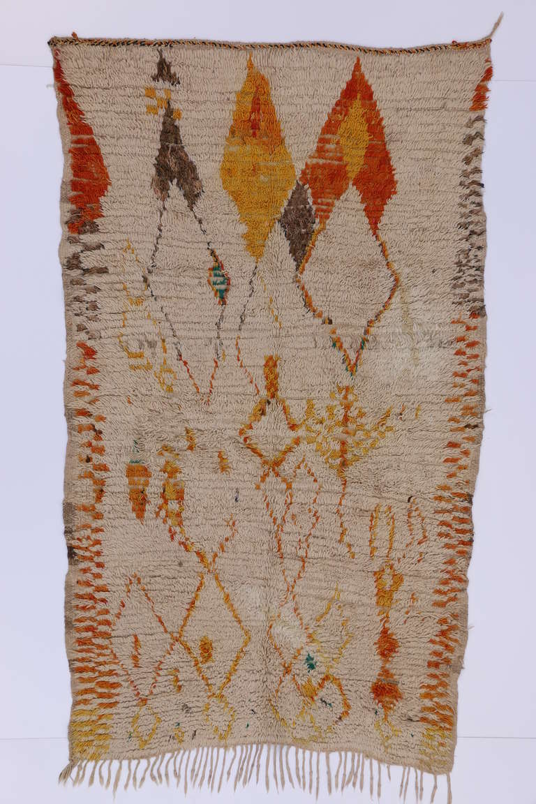 This unique Moroccan rug has a geometric latticework that creates a modern and abstract look. This piece has splashes of light brown, orange, and yellow that give this Moroccan piece its eclectic modern look. These Moroccan rugs are 100 percent