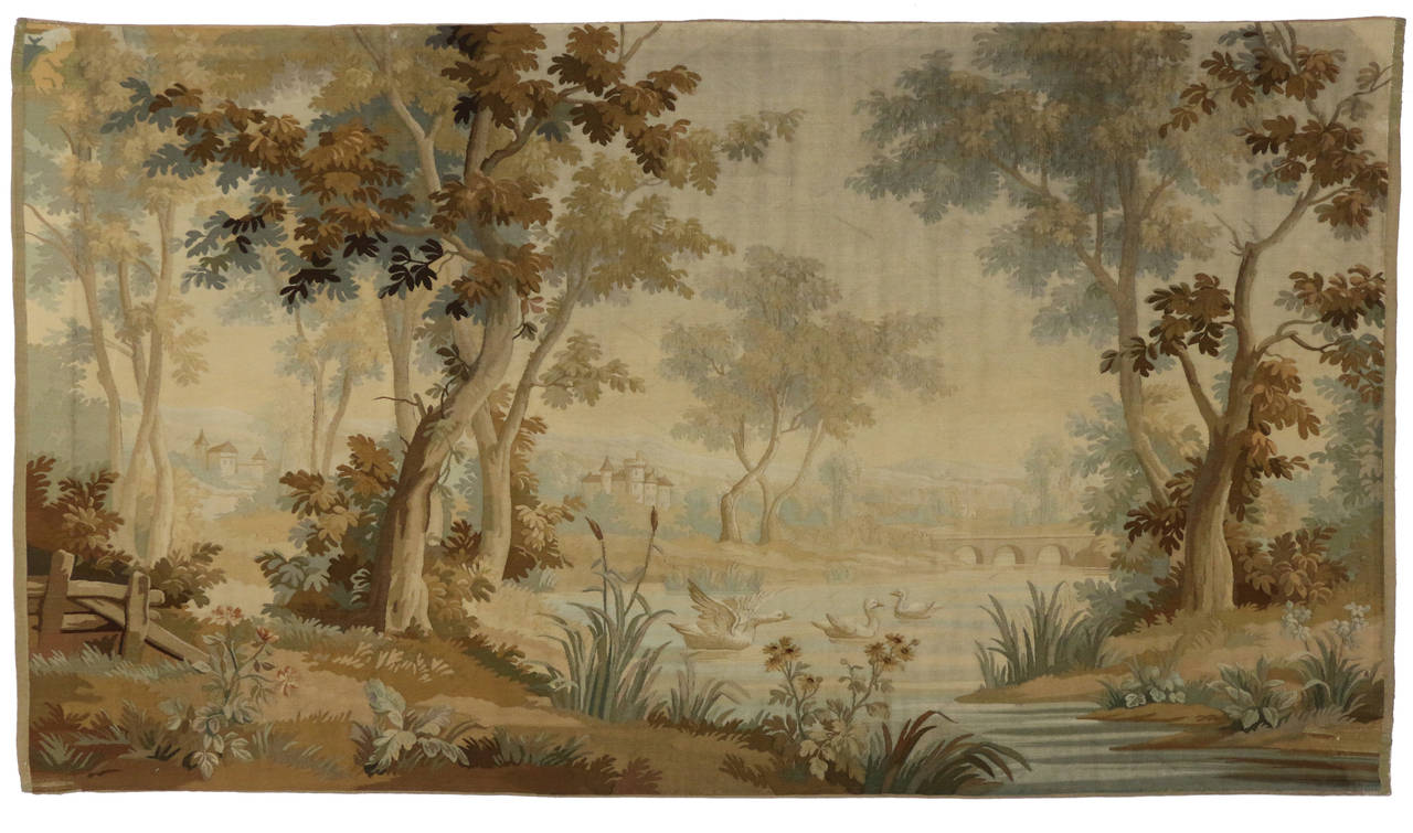 This beautiful Aubusson Tapestry has a landscape of the countryside depicted by a river and groups of trees and plants surrounding the river. This foreground of this piece is clear while the background fades out and has an illusion that the image is