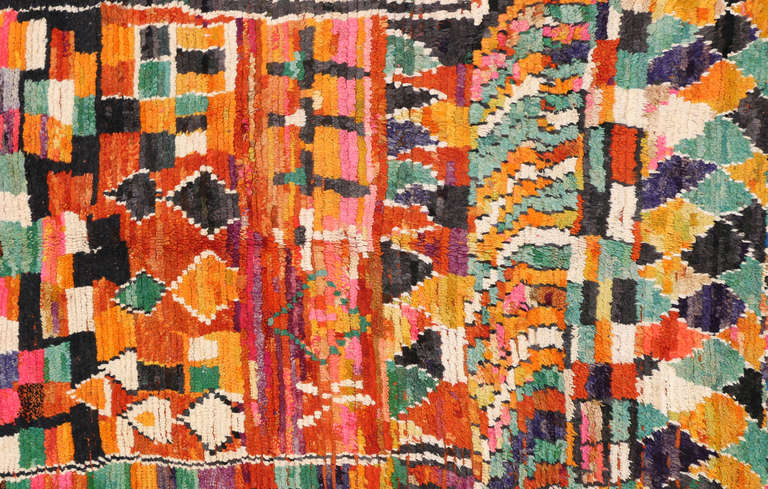 This beautiful multicolored vintage Moroccan rug has hues of green, orange, yellow, pink, and black. This piece has an all over pattern that progresses from diamond to square.