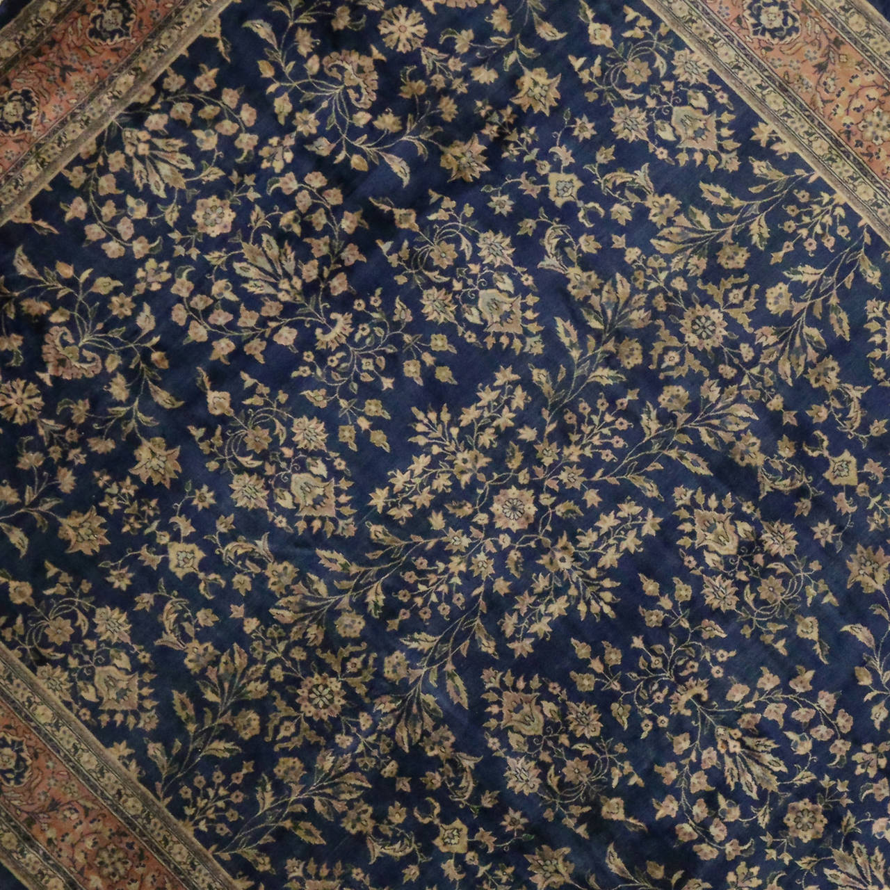 This antique Agra was hand knotted in India during the early twentieth century. It features a traditional, yet elegant composition characterized by an allover pattern unfolding a balanced palette of navy blue, muted rust, ivory and shades of green