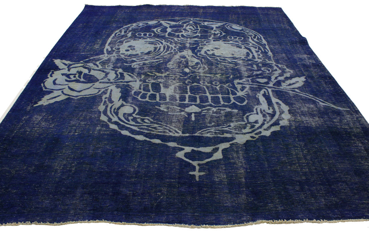 This overdyed vintage Persian Tabriz rug in blue is far from plain and simple with its alluring and meaningful composition. In this unique distressed rug, the intricately illustrated skull and rose has been given a sophisticated twist by designing