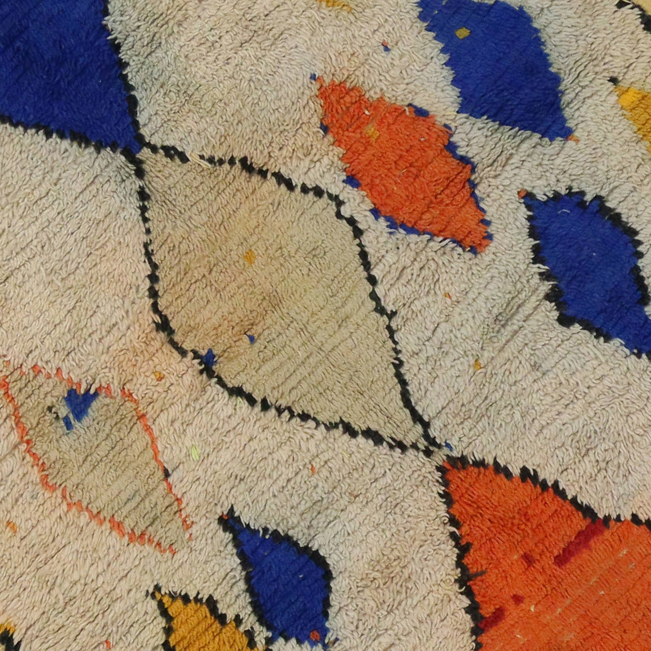 Transform your interior space into a Moroccan delight with this vintage Moroccan rug. With an energetic color palette consisting of orange, blue, yellow and black on a field of ivory represents the contemporary, yet authentic creative and archaic