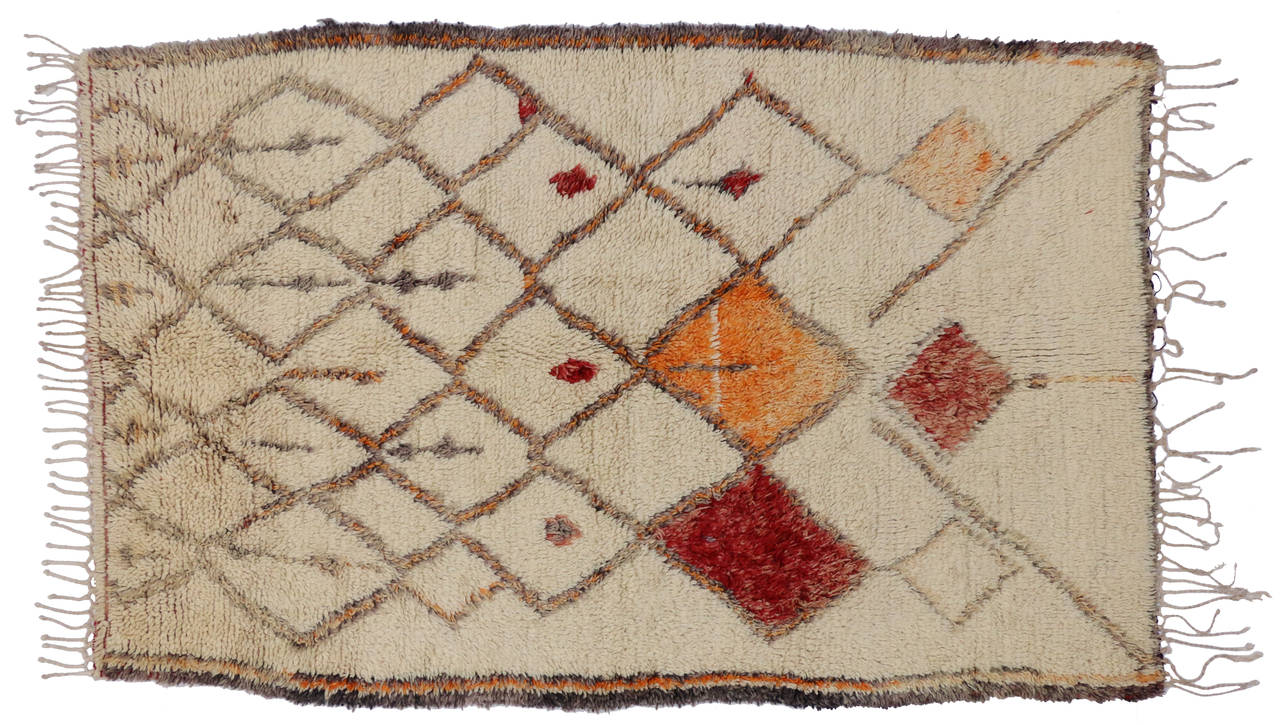 This eclectic vintage Moroccan Azilal rug has a unique tribal design with warm colors of red, orange and shades of grey. Azilal rugs with their thick pile and sturdy weave make them an ideal statement rug for nearly any room. The Berber women, for
