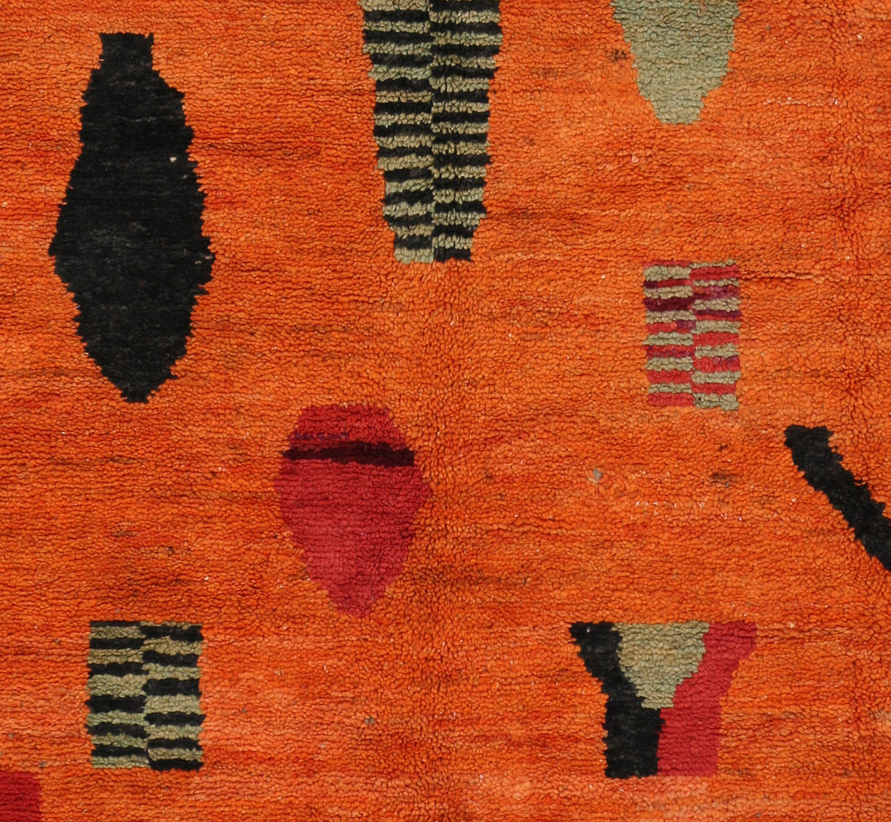 This Mid-Century Modern Moroccan rug was made by the Berber tribes of Morocco. Featuring hues of black, soft green, crimson red and speckled flecks of lavender contrast nicely on the charismatic orange field. Let this vintage Moroccan carpet