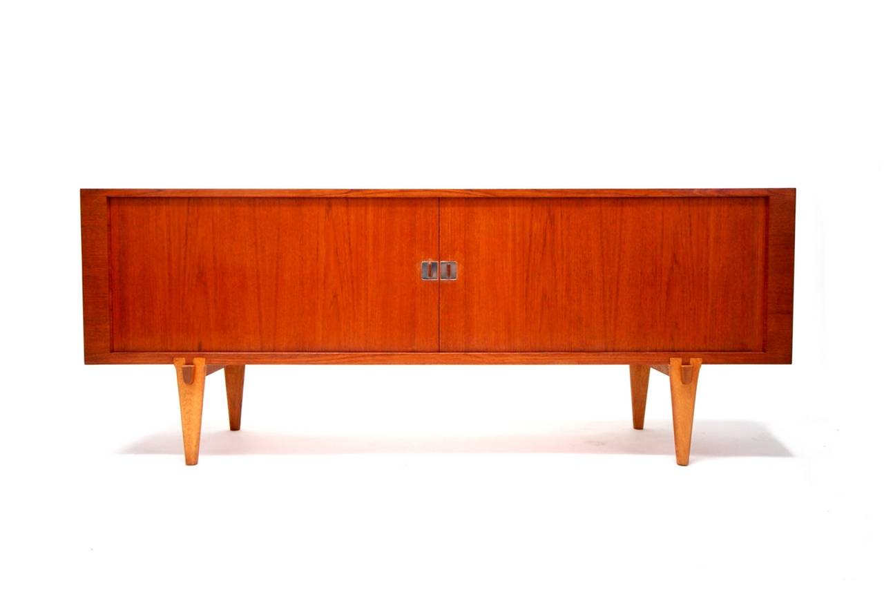 "President" credenza designed by Hans Wegner, and produced by Ry Mobler of Denmark, circa 1965. The teak cabinet features two sliding tamboured doors concealing a soaped oak interior with three compartments. The center compartment