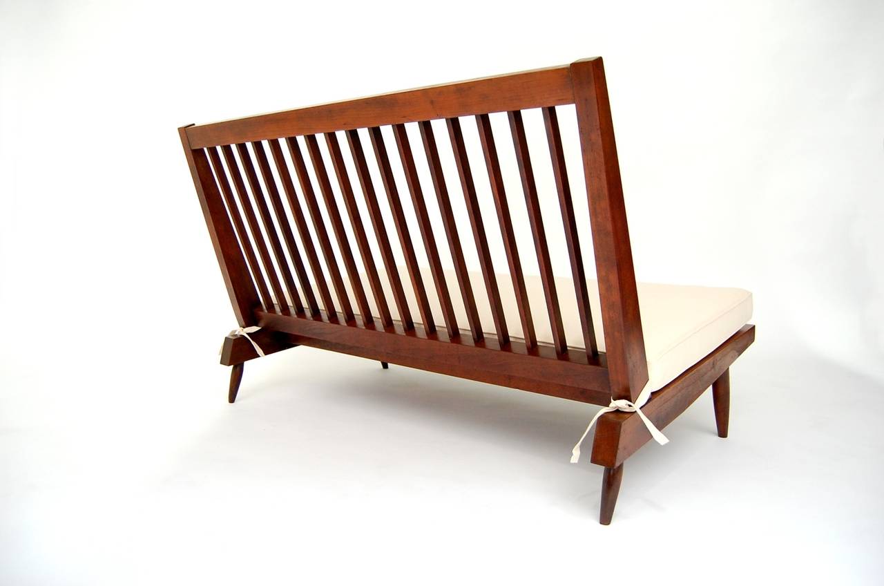 Studio made slat back settee in walnut, circa 1955, by Japanese American Craftsman George Nakashima (1905–1990). Settee currently has one newly made loose cushion, but we can have one made for the back as well, if client so desires. Excellent