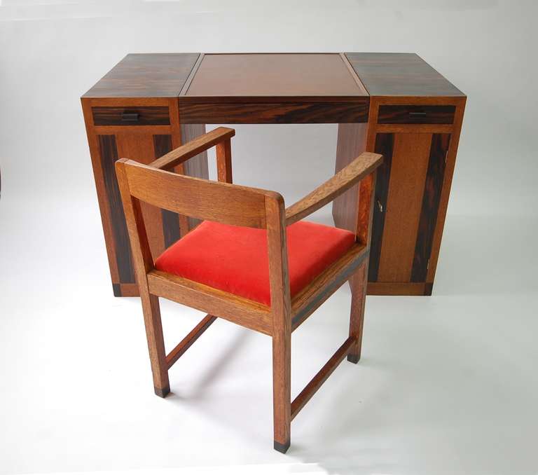 Game table or desk attributed Francis Jourdain, France, circa 1930. Fumed oak and palisander, with leather top. Center top flips open to reveal a red aniline dye storage compartment. Two flanking drawers, locking door to right concealing adjustable