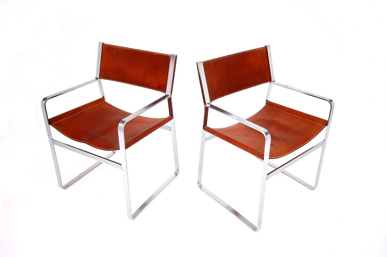 Rare pair of JH-813 armchairs by Hans J. Wegner with frames of flat steel and original handstitched saddle leather. 

Sketched in wood by Wegner in 1947 for the Copenhagen cabinet maker's guild exhibition, but not actually manufactured until the