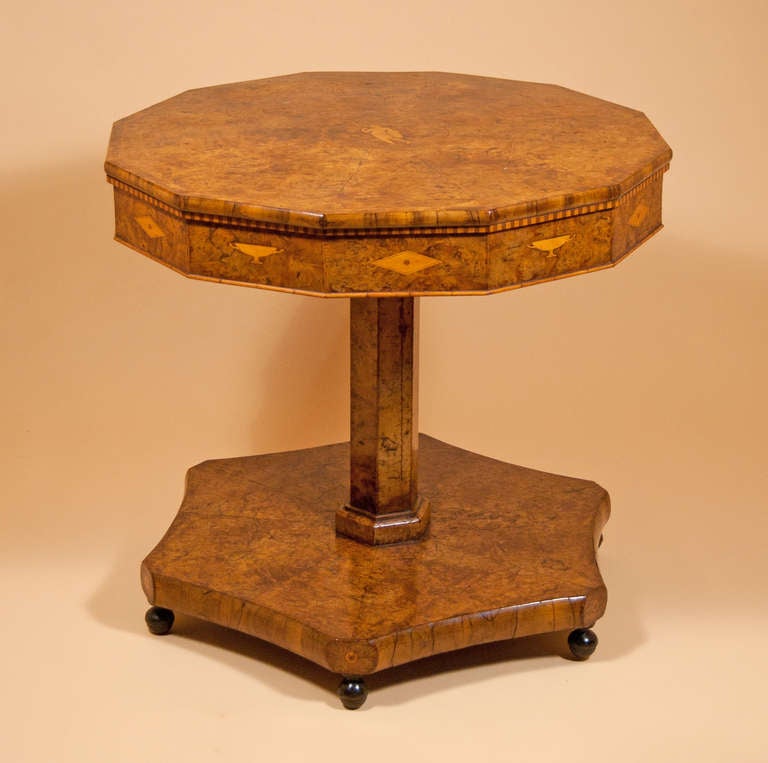 Burr yew wood:  the 12-sdied top veneered in radiating fan segments with central medallion inlaid with a classical figure in the centre and with a cross-banded border. The frieze is inlaid with a checkerboard banding and enriched with alternating