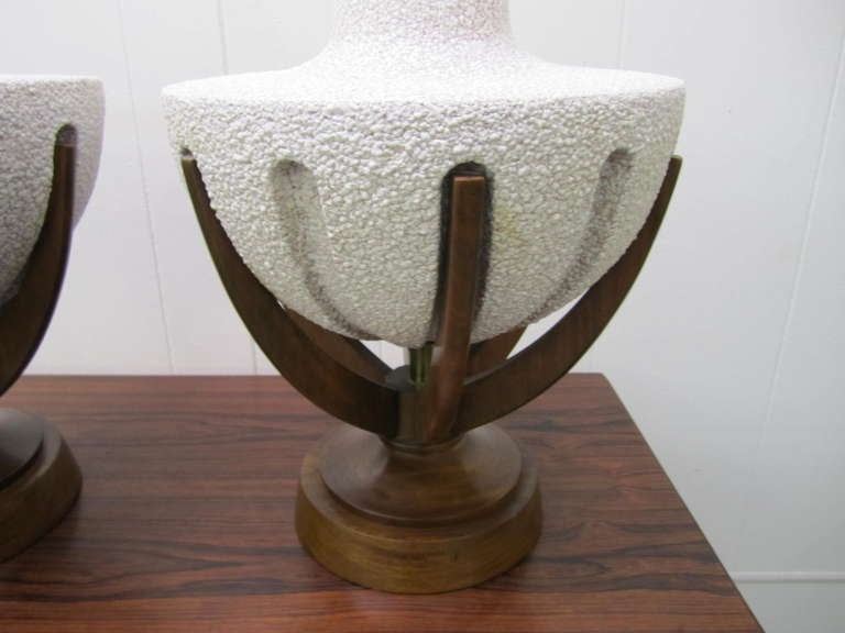 Amazing pair of huge danish modern sculptural walnut pedestal lamps.  Well crafted carved walnut bases hold like fingers the textured white ceramic lamps. The lamps are a whopping 40.5