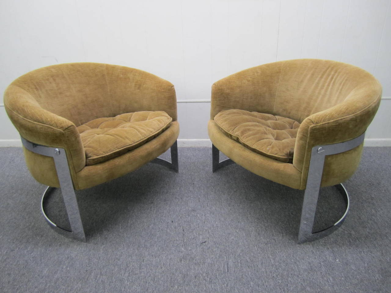 Stunning pair of barrel back chrome flat bar lounge chairs. These chairs are in vintage condition with their original light brown velvet fabric in usable condition. The thick chrome flat bars are in fabulous condition with only very light signs of