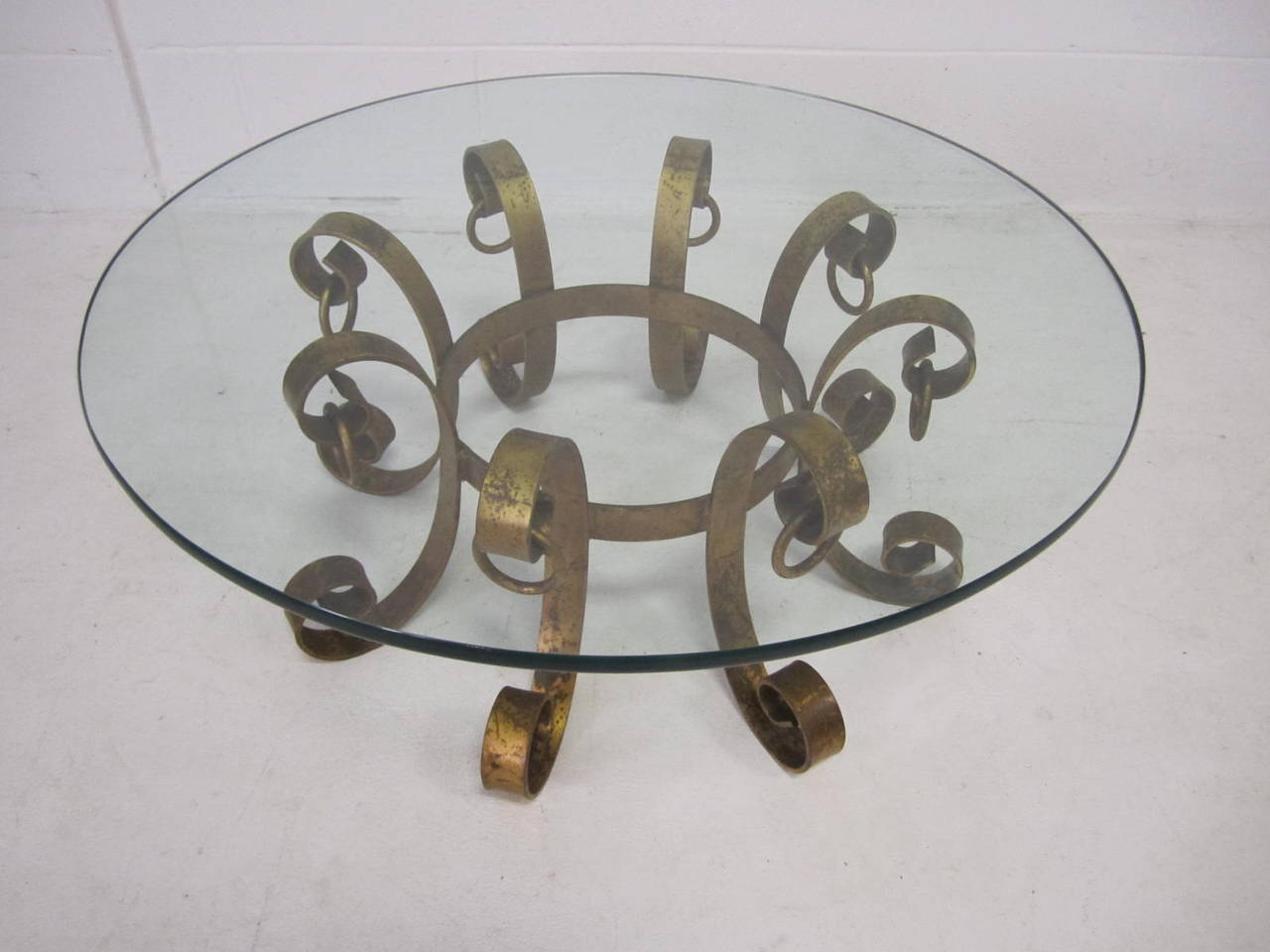 Stunning Gilded iron scroll coffee table. This piece has  has a wonderful distressed gold finish and is very heavy.  The glass is very thick and looks fabulous with the sculptural iron base.