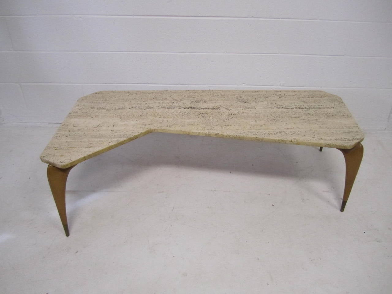 Sensational Gio Ponti style boomerang shaped travertine coffee table. Sensuous sexy light wood legs support a super organic textured travertine top. The wonderfully carved legs are capped with a handsome brass sabot. This coffee table is truly