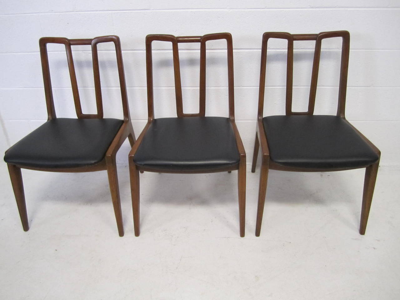 Handsome set of 5 John Stuart walnut dining chairs.  This well crafted set consists of 2 arm chairs and 3 side chairs.  The seat seats pads have newer faux black leather and look great.  We love the large scale of the arm chairs.
