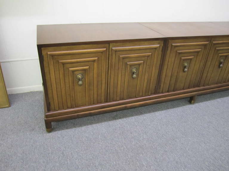 This credenza by Renzo Rutili for Johnson Furniture has a set of three cabinets that have a beautiful carved front doors. All three cabinets are placed on an elevated cabinet base. The gorgeous carved front doors open to reveal three open cabinets