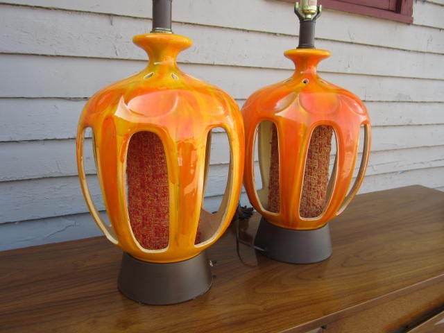 STUNNING AND COLORFUL PAIR OF MID-CENTURY MODERN DRIP GLAZE LAMPS WITH PEEK-A-BOO CUT OUTS.  THIS PAIR IS SURE TO BRIGHTEN UP YOUR MID-CENTURY MODERN DECOR.  THE BOTTOM PART HAS A LAMP FOR MOOD LIGHTING. THESE ARE LARGE SCALE AND SURE TO PLEASE.