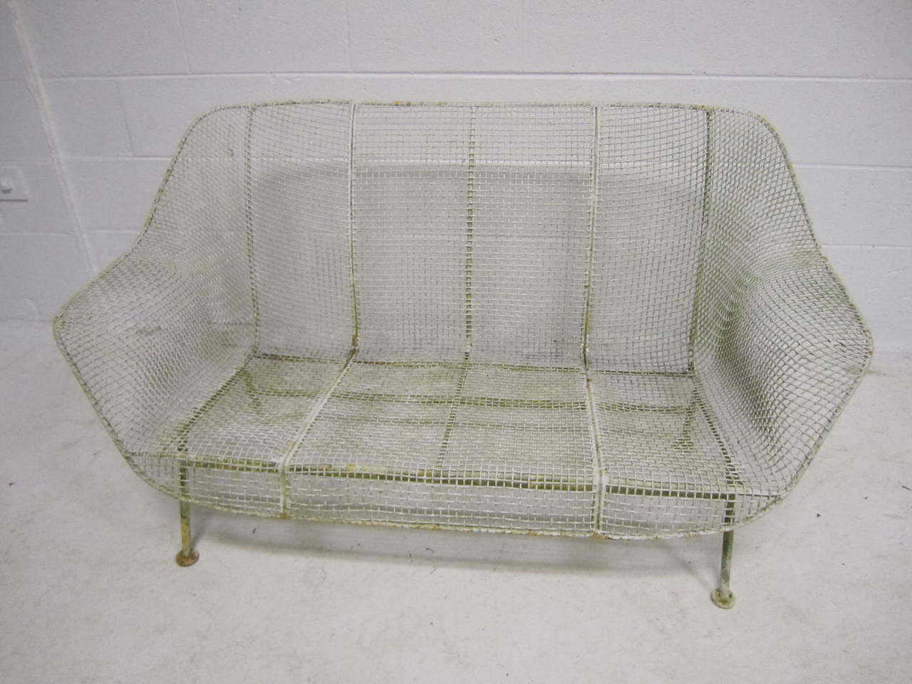 A vintage 1950's wrought iron and steel mesh settee from Russell Woodard's classic and iconic Sculptura series. Beautiful and classic sculptural design. This piece retains it's original finish which does show some age-we like the vintage look but we