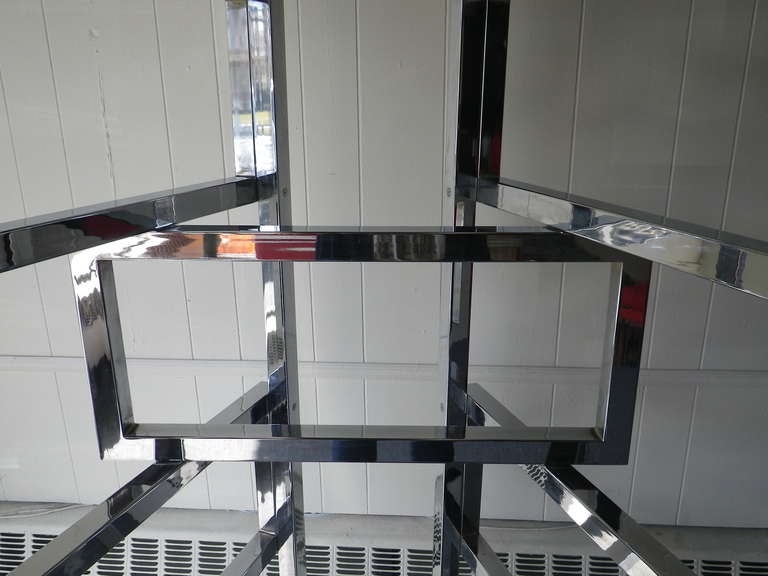 Over the top Milo Baughman chrome and glass etagere.  The chrome plated steel heavy square tubes are hinged to allow for the units panels to pivot.  The chrome is very nice with only minor  signs of wear.  The glass shelves can be arranged in