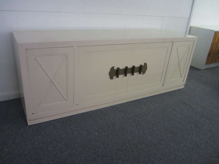 Lovely signed Grosfeld House cream lacquered hanging credenza. Heavy solid brass hardware shows a nice vintage patina. This piece has a beveled hanging bar along with the original beveled rail that attaches to the wall to allow the cabinet to appear
