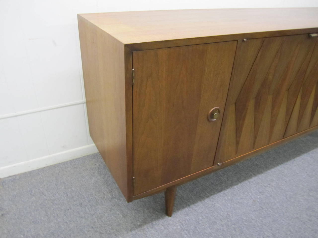 Fantastic Mid-Century dresser with gorgeous front diamond detailing, sculptural legs, finished in a rich medium walnut. The fabulously carved walnut doors open to reveal two drawers and an open space below. The doors on either side open to reveal