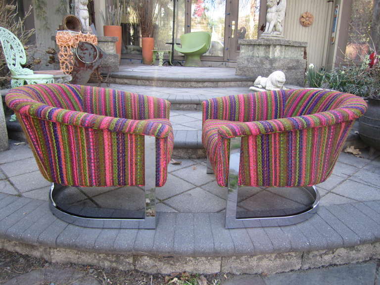 Sensational pair of Milo Baughman style chrome flatbar barrel back lounge chairs. These chair have everything going for them-shiny thick chromed steel flatbar base with a mirrored polish and fabulous original ultra mod strip upholstery.  To be