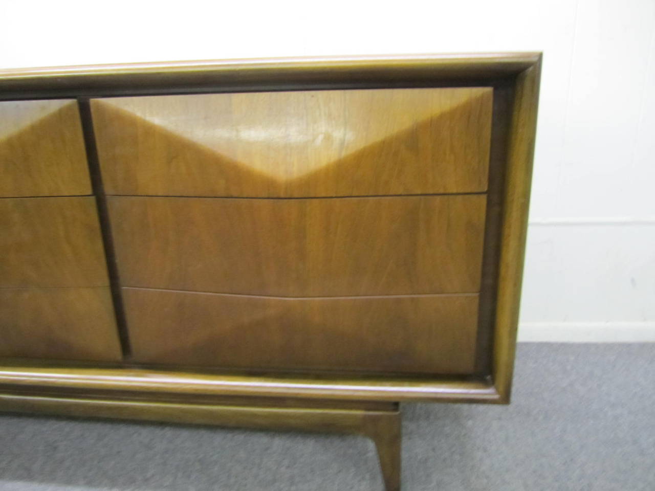 Sleek, Classic, modern, Mid-Century walnut three-dimensional diamond front credenza. The nine drawers provide ample storage functioning perfectly as a bedroom dresser or credenza. This piece is in very nice vintage condition. We do have more than