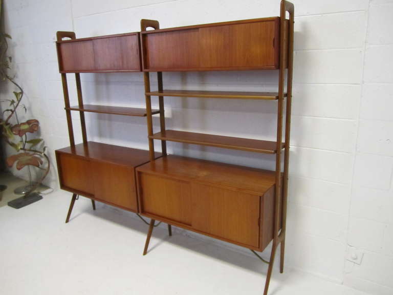 Kurt Ostervig Danish modern open two-section teak wall system. Features four height adjustable shelves, two sliding door larger lower cabinet and two smaller sliding door upper cabinets. This wonderfully crafted teak wall unit can be used as a room