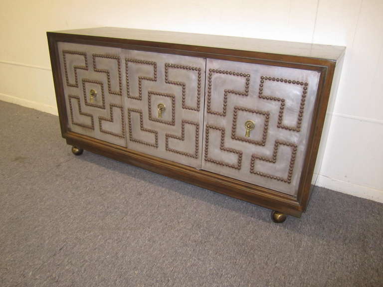 Stunning pair of brass studded petite credenzas in the style of Parzinger. Metal clad fronts with lovely brass tacks and solid brass tassel pulls. The tops have wonderful faux slate textured Formica which looks gorgeous and so very useable. The