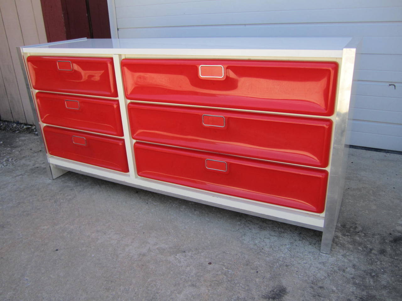 Fantastic pop modern red plastic front credenza. Wonderful chrome details accent the edges and the top and sides are white lacquer. Great piece for a bold statement in any room.