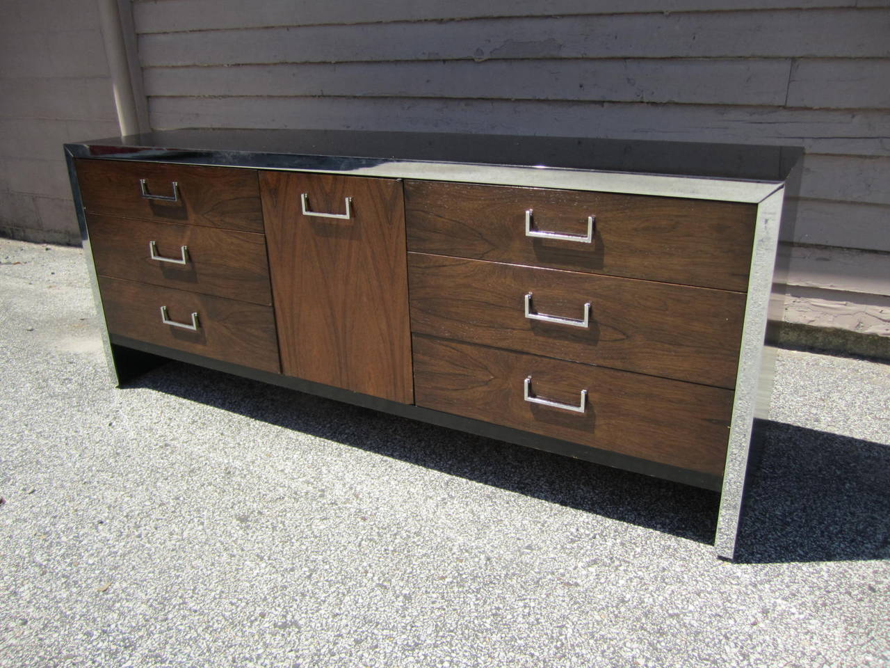 A long black lacquer and rosewood dresser in the style of Milo Baughman.  Consists of six drawers with a center cabinet including three smaller drawers. Chrome trim and handles are clean and bright. Rosewood veneer is in very nice condition. A