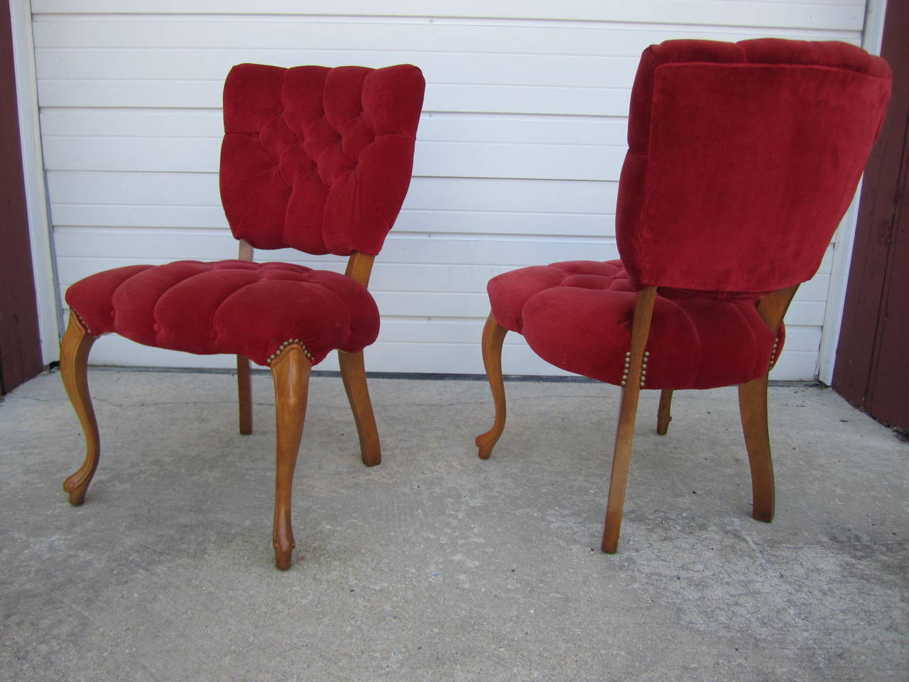 Lovely pair of Queen Anne style red velvet tufted side chairs. These chairs are circa 1950s and have great vintage appeal. They retain their original red velvet in presentable condition-we recommend re-upholstery. We love the sexy lines of the curvy