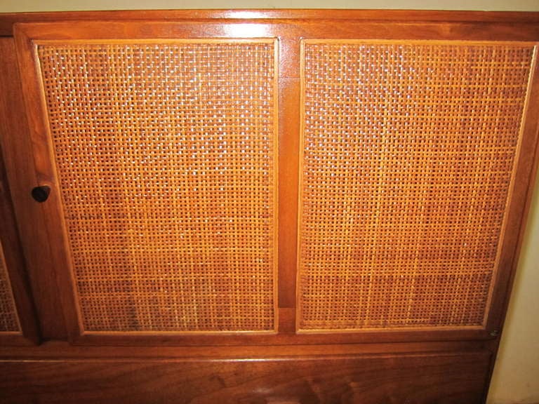 Unusual walnut Conant Ball caned front tall dresser.  This piece has danish influences but is extremely well crafted like American modern furniture.. The caned front doors open to reveal some lovely cubbies.  Notice the very neat carved walnut pulls