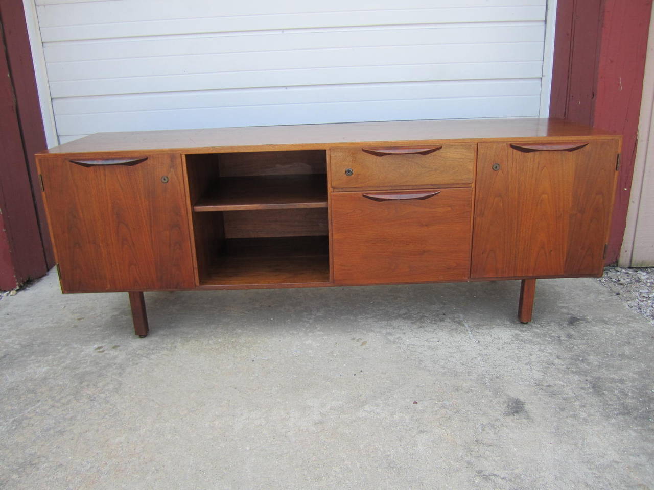 Walnut Jens Risom credenza. Two cabinet doors with an adjustable shelf inside. Also has two drawers and one open space with adjustable shelf. Credenza has a finished back. This is an awesome solid walnut cabinet / credenza designed by Jens Risom.