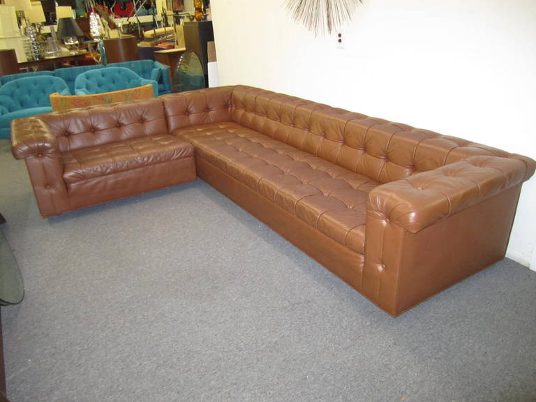 A generously proportioned L-shaped sectional Chesterfield sofa with tuck and roll button tufted original leather upholstery.  This amazing set of sofas retains their original caramel colored leather in wonderful vintage condition.  Worn in just