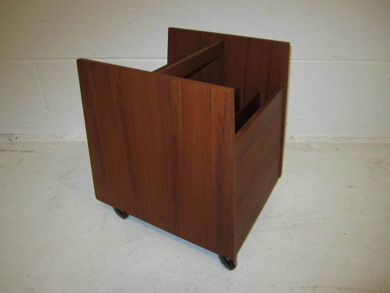 A vintage magazine rack in teak wood on casters. The piece has the original label for Bruksbo of Norway.