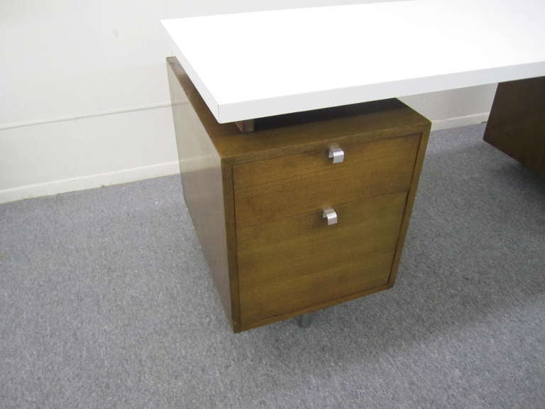 A mid century modern executive desk designed by George Nelson and made by Herman Miller. Walnut with a floating  white laminate top and chrome legs and pulls.