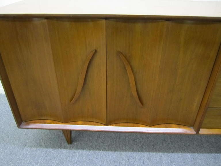 Lovely american modern walnut credenza. Very interesting details with large sculptural pulls and nicely carved legs. I have the matching night stands and tall dresser if your looking for additional pieces. Wonderful scalloped front doors open to