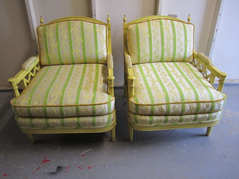 Lovely pair of yellow regency modern oversized lounge chairs.  I love all the details with the finials and carved gothic style arms.  The finish is also quite unique being a lightly distressed painted yellow.The fabric looks to be original and is