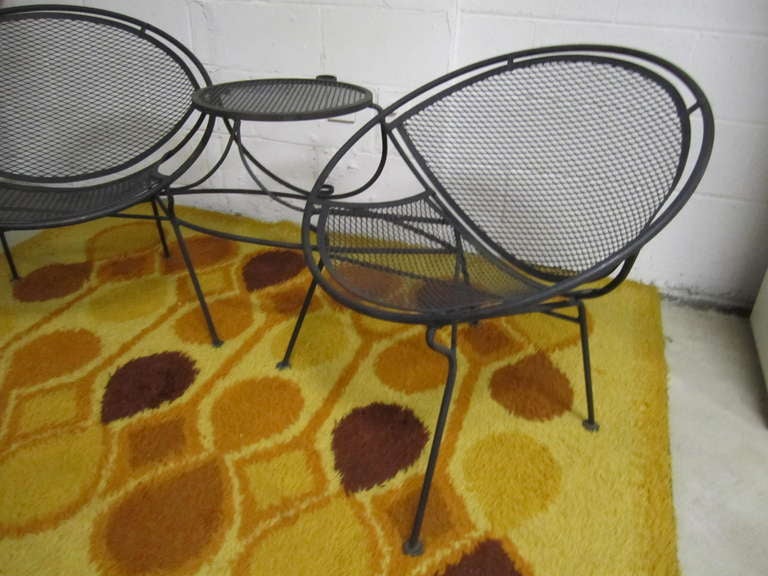 Rare Mid Century Modern clamshell Tete a Tete by Maurizio Tempestini for Salterini. Made of iron this practical and classic design has a connecting table as well as an umbrella holder to offer shade.  You will love the quality and craftsmanship of