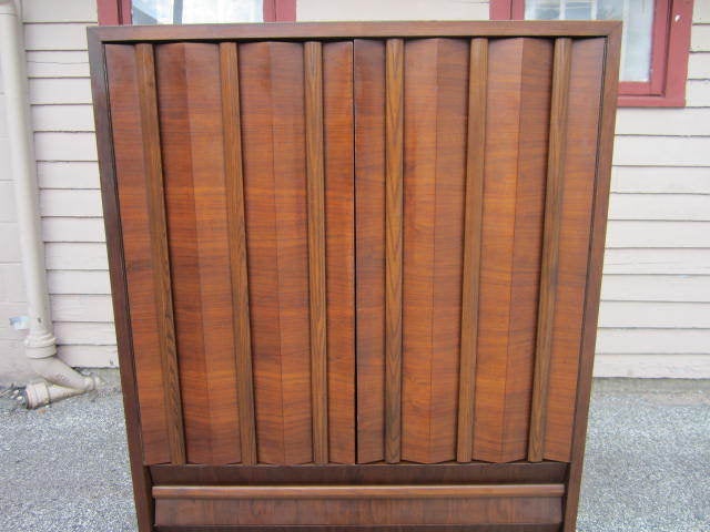 Gorgeous mid-century modern tall walnut dresser on a pedestal base.  Very unusual design paired with tons of storage make this an ideal piece for bedroom or any living space.  The chunky walnut doors open to reveal 4 pullout drawers and 2 adjustable