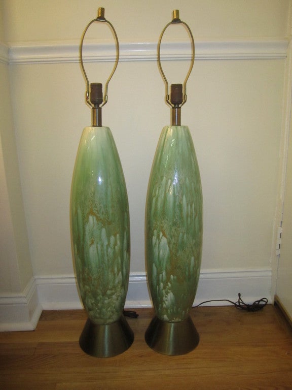 Large-scale pair of tall slender ceramic drip glazed lamps. The colors are exceptional in celery green with drips of cream and golden ochre. Conical shaped brass bases look fantastic with the ceramic pottery. These lamps measure 39.5