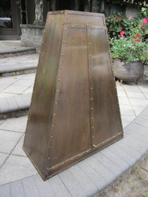 Fabulous and rare patinated brass trapazoid hanging wall cabinet.  I love the vintage patina of the brass.  The doors open to reveal space for your bottles or bar wear.  This amazing and rare piece is in great vintage condition.  When i originally