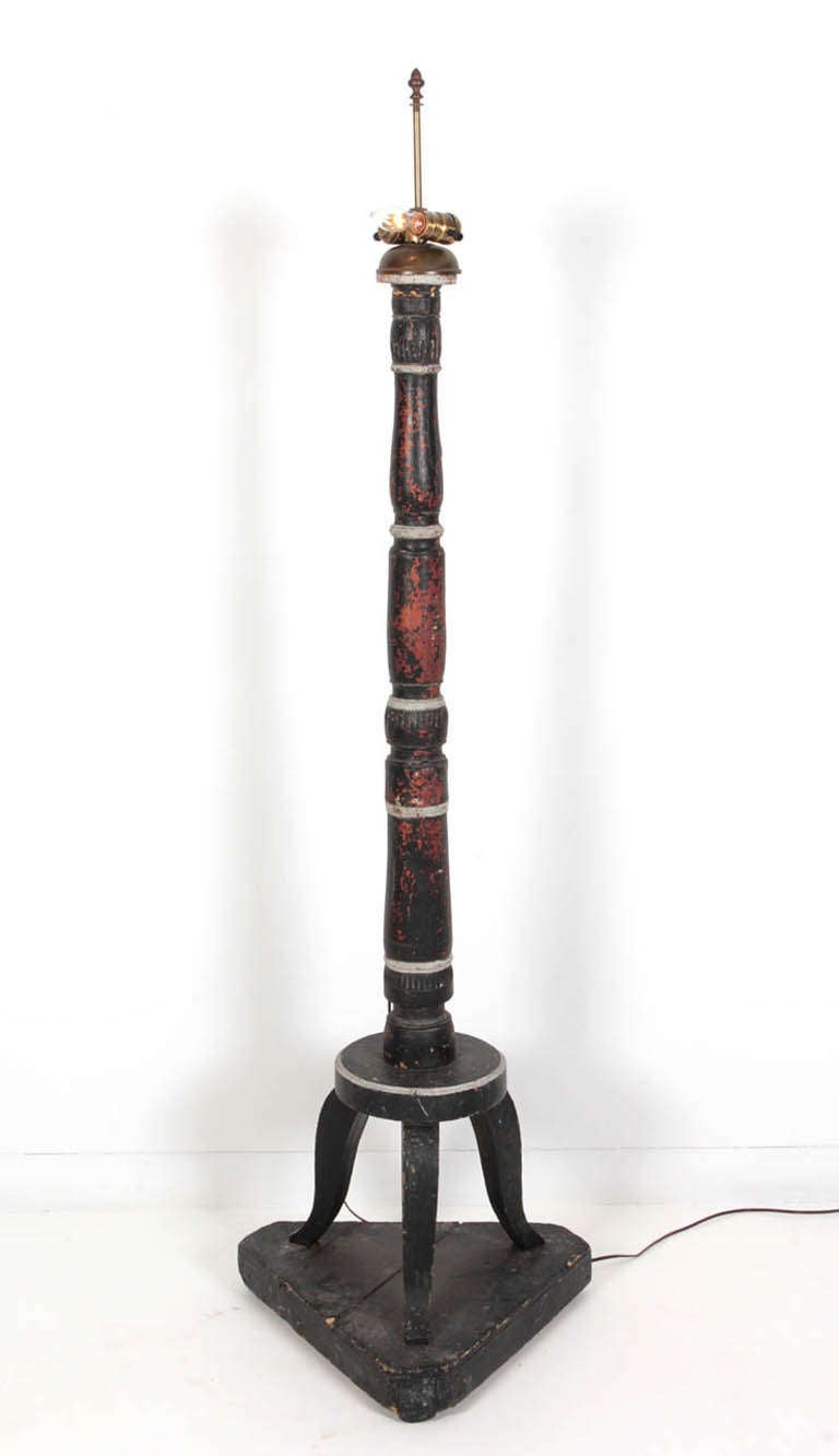 Black wooden Folk Art floor lamp. Tri-pod legs on a original triangular stand. Newly made into a electrified lamp, originally a large candlestick.