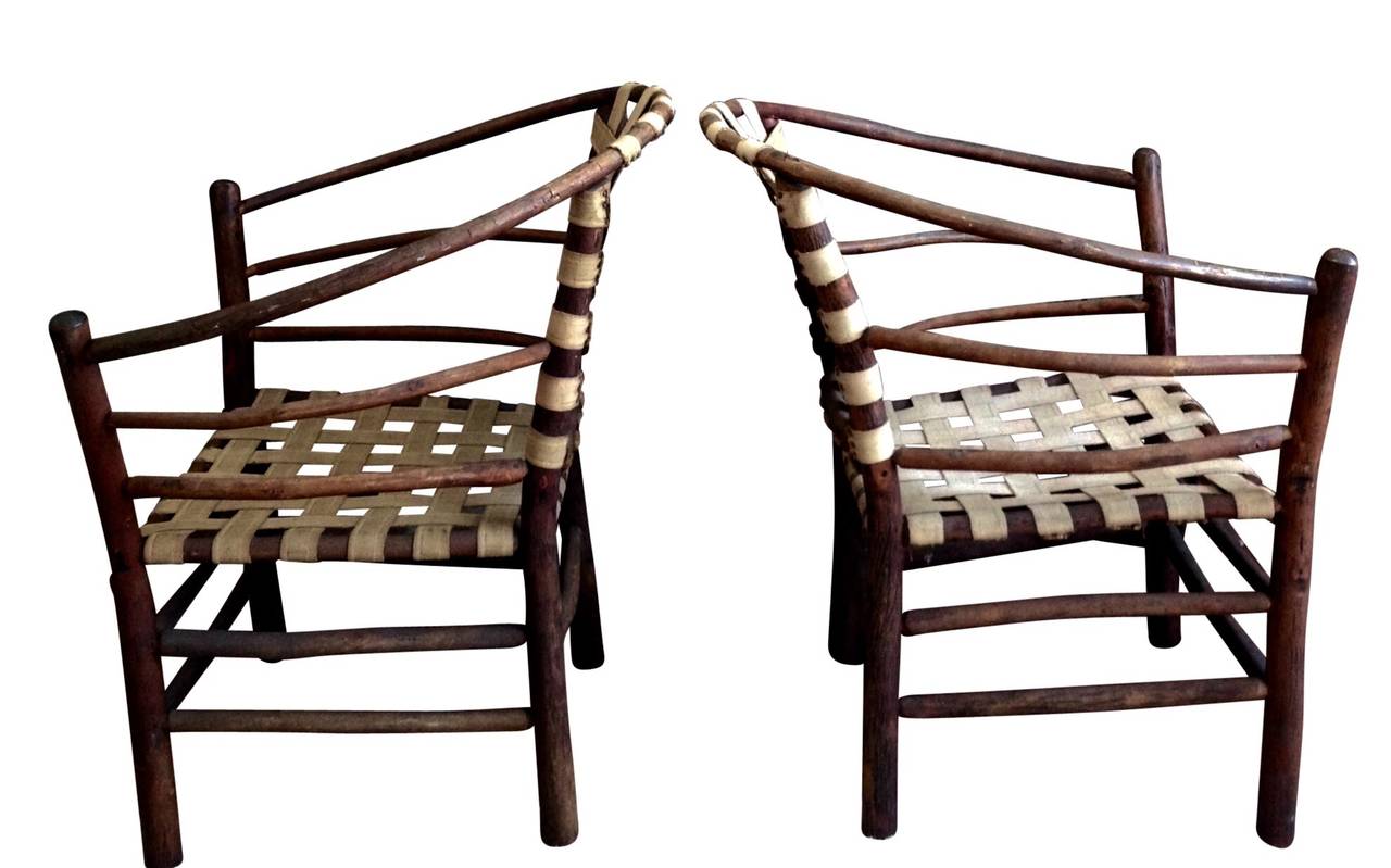 Pair of beautiful vintage Adirondack armchairs with original rustic finish and webbing.