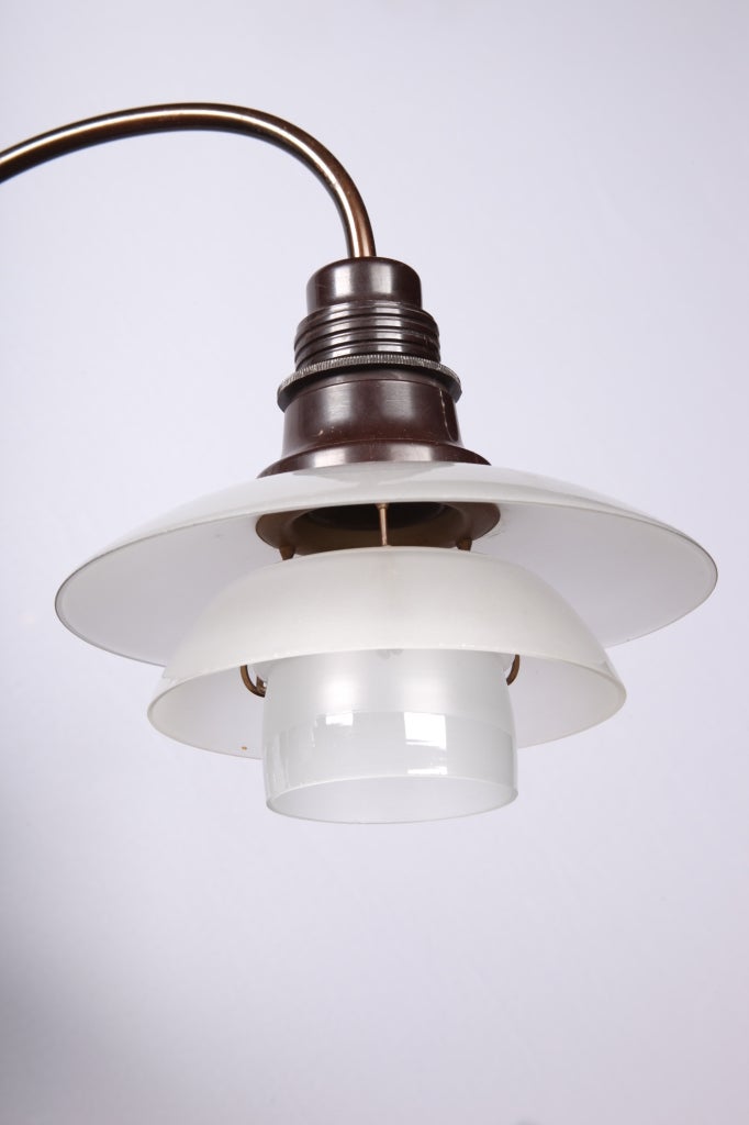 3-armed PH chandelier with browned brass frame, sockethouse of brown bakelite, 3 opaline glass shades.
Manufactured by Louis Poulsen.