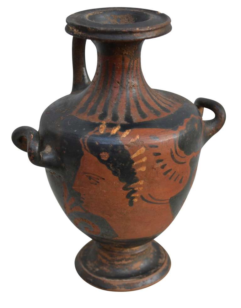 Small Apulian redfigured hydria, South Italy. Hydria decorated in black glaze and white colour with female head in profile. 

Provenance: From an old Danish collection.

A hydria was used for water and was typically larger in size. This hydria