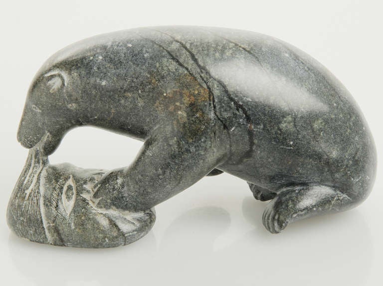 This is an interesting inuit piece in a tight black granite stone.
Signed Adamie.  It is said that a bear is a strong totem or spirit animal and if a hunter accepts being eaten by a bear, he will be reincarnated into a shaman and carry the spirit