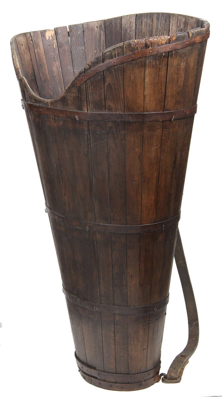 This is a large harvest basket, most likely made around the turn of the century. The conical wood form is made of pine and has
metal straps with both handmade and commercial nails. the wood has a wonderful warm patina.