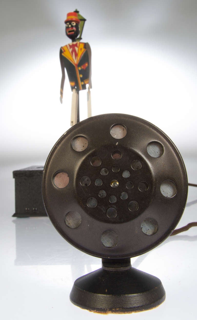 This piece is in beautiful condition and has its plug-in original circular speaker.
The articulated and painted dancer, standing beside a lamppost is on blue dance pad. The base is painted black with a crackle texture. The microphone wire is 57